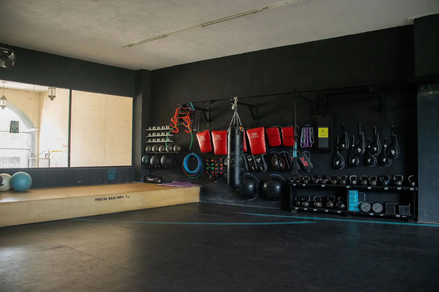 Salón funcional con costales, kettlebells y piso de bajo impacto